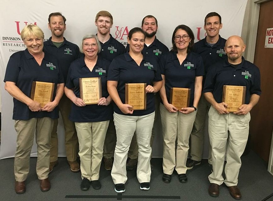 Small group of employees holding plaques.