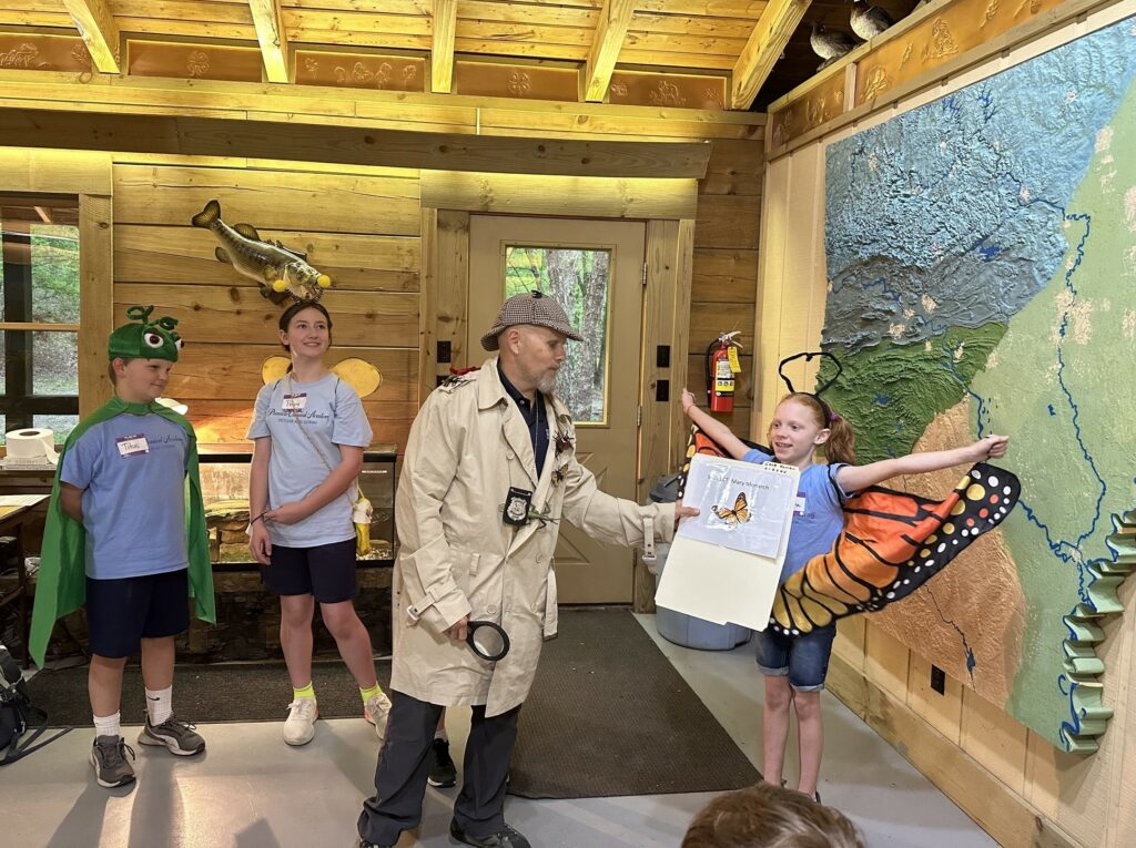 Man in hat and coat talking to a girl dressed as a butterfly.