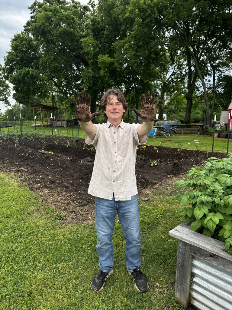 man holding out his hands covered in soil